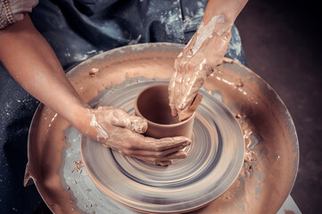 hands of potter do a clay pot