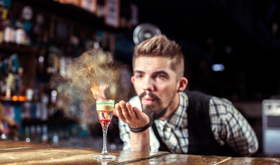Portrait of bartender creates a cocktail in the pub