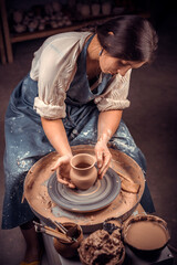 Beautiful young woman master demonstrates the process of making ceramic dishes using the old technology. Handwork.
