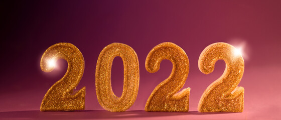 New Year banner with golden sparkling number 2022 against violet background.
