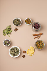Different types of tea and herbs in bowls on a beige background