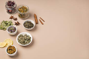 Different types of tea and herbs in bowls on a beige background