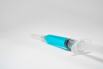 Syringe with blue liquid on white background