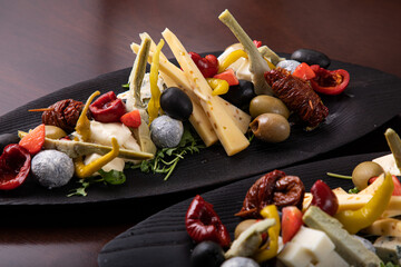 Palette of many types of cheese and some vegetables, tomatoes, paprika, olives.