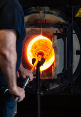 Man glass blowing at glory hole. Red hot.