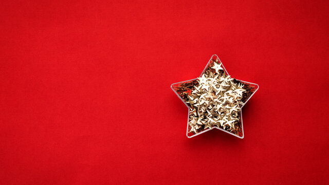 Golden stars confetti in star shape box on red background. Christmas stock image