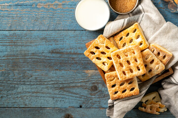 Puff cookies square in a wooden box on a blue wooden culinary background. Delicious homemade sweet pastries closeup	