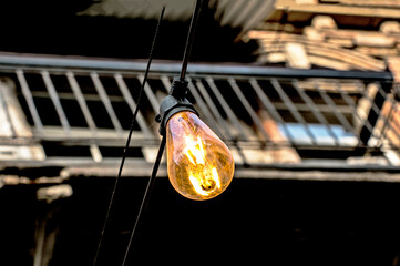 Background image of an outdoor lamp, focus on a classic light bulb with wiring.