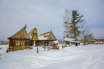 The winter village of Krasny Yar of the small indigenous peoples of the north of Russia - the Udege. Street in the village in winter. Wooden Russian huts in a beautiful village.