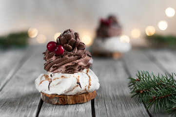 Delicious cake with chocolate cream on the background of festive lights with fir branches. Selective focus with blurred background and foreground and copy space