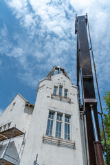 Repair of the old wooden roof of a beautiful historical building. The crane lifts the builders to a...