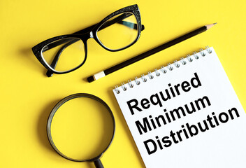 Required minimum distributions RMD phrase written on a notebook with glasses, magnifying glass and...