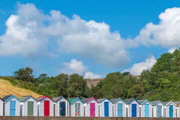 Fototapeta na wymiar Colourful beach houses. Row of multicolored beach huts against blue sky.