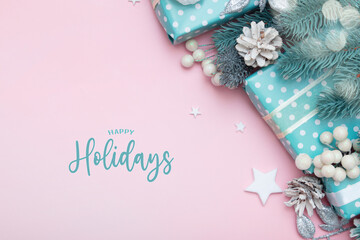 Happy holidays greeting card with christmas gifts, berries and pine flat lay on pink background with copy space