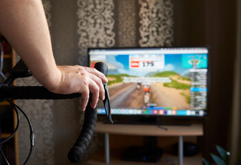 Cyclist is training on the bike with a TV doing online cycling. Stay fit and active while at home....