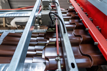 Production line or conveyor belt of metal tile for roof production. Metalwork factory. Metal sheet...