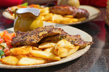 Fried meat with baked potatoes and fresh salad on a beautiful ceramic plate. food in the restaurant. close up