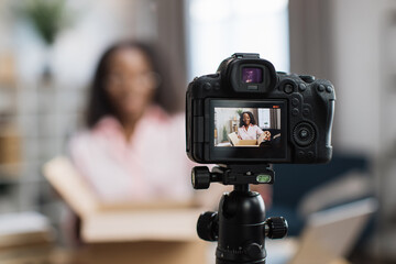 African american woman unboxing parcel with ordered goods while sitting at home and recording video...