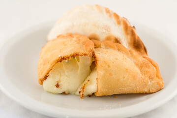 empanada caliente rellena de queso derretido cortada a la mitad