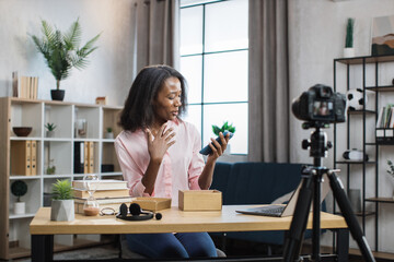 African american woman doing live stream while unpacking box with new smartphone. Female blogger sharing her feedback about modern gadget with her subscribers.