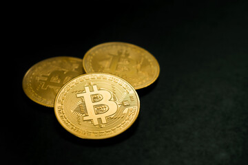 three close-up bitcoin coins on black background
