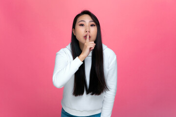 Pretty young asian girl holding finger on lips show silence gesture, ask to keep secret. Privacy....