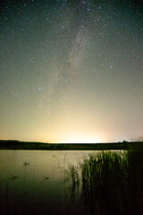 milky way and reeds  stars over the lake at night lights . Lake over the nightsky	
