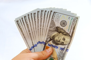 Girl holding dollars in her hands isolated on white background. One hundred dollar bills.