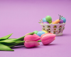 Fototapeta na wymiar Easter eggs in basket with pink tulips in a modern background.