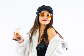 Young brunette girl in black hat celebrating New Years Eve on a white background. I challenge the model with a very cheerful glass of champagne