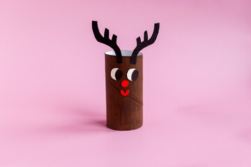 Holiday easy DIY craft idea for kids. Toilet paper roll tube toy cute deer on pink background....