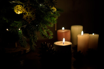 many lighted candles near the Christmas tree. Photo in dark colors. Copy space - 473215665