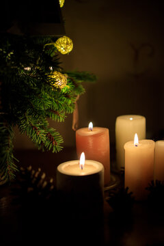 many lighted candles near the Christmas tree. Photo in dark colors. Copy space