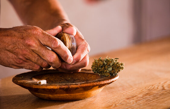 man hands with marijuana grinder at home