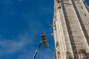 Technicians on lifting platform for scheduled maintenance plan and study of the degradation phenomena of the Milan cathedral
