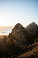 A beautiful beach with two big rocks on it, at sunset, in a beautiful landscape with nice views