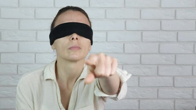 Blindfolded feminist. A blindfolded woman points her finger.