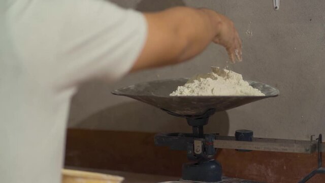 man weighing grams of flour to make bread