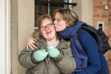 Tienen, Flanders  Belgium - 07 20 2018: Portrait of a young white woman kissing a woman with Down...
