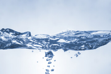 Water splash on blue background. Aqua flowing in waves and creating bubbles. Drops on the water surface feel fresh and clean.