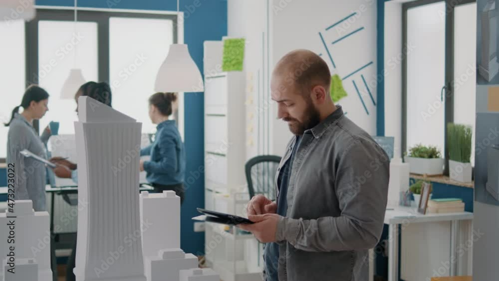 Aufkleber man engineer designing architectural plan on tablet with building model and maquette. architect work