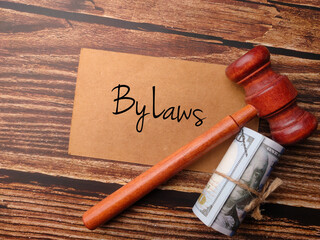 Gavel,banknotes and brown card written with text By laws on a wooden background.