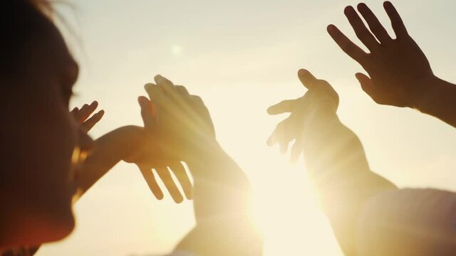 happy family people group pull hands to the sun teamwork. silhouette people party dancing recreation holiday. people at a music concert pull their hands up. lifestyle religion sunlight concept