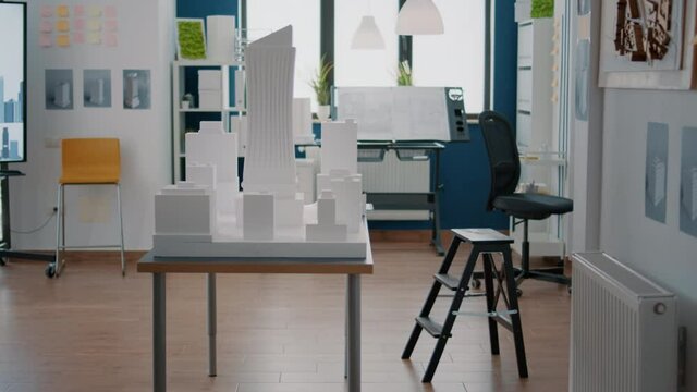 Empty architectural space with buidling model and maquette to create property plan on desk. Nobody in work office with construction layout and design used for urban development project.