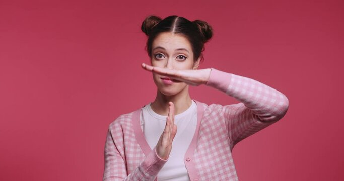 Young stylish teen brunette girl in pink clothes doing time out gesture by hands over isolated pink background. Stop and get pause concept. Slow motion