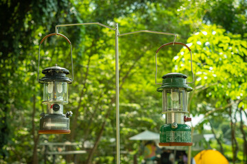 Close up Beautiful double vintage camping lantern hanging on a steelstand with a background of tents in the camping,Relaxing in the midst of nature