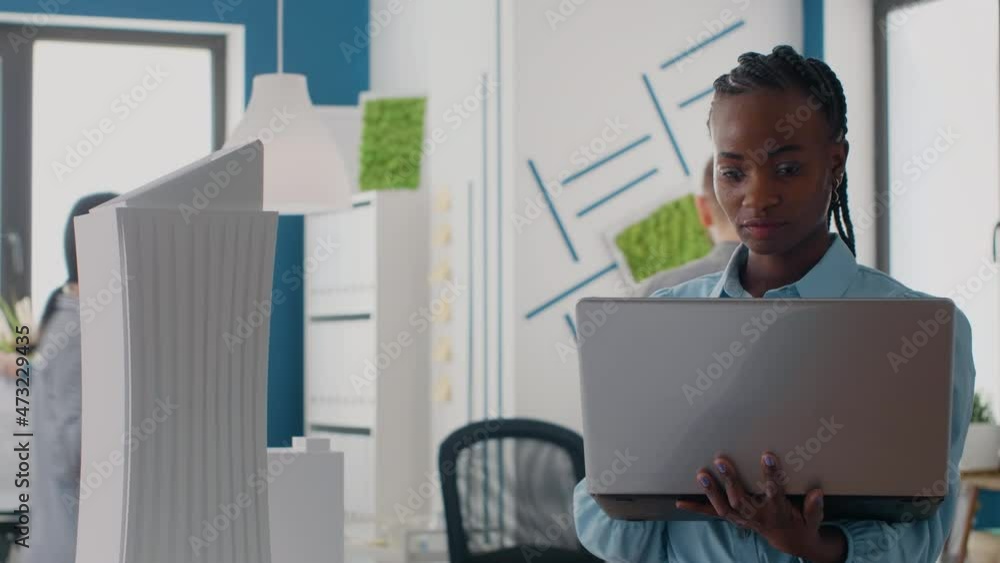 Aufkleber Close up of engineer looking at laptop to analyze building model in architectural office. Woman builder using computer and maquette to design construction layout for development.