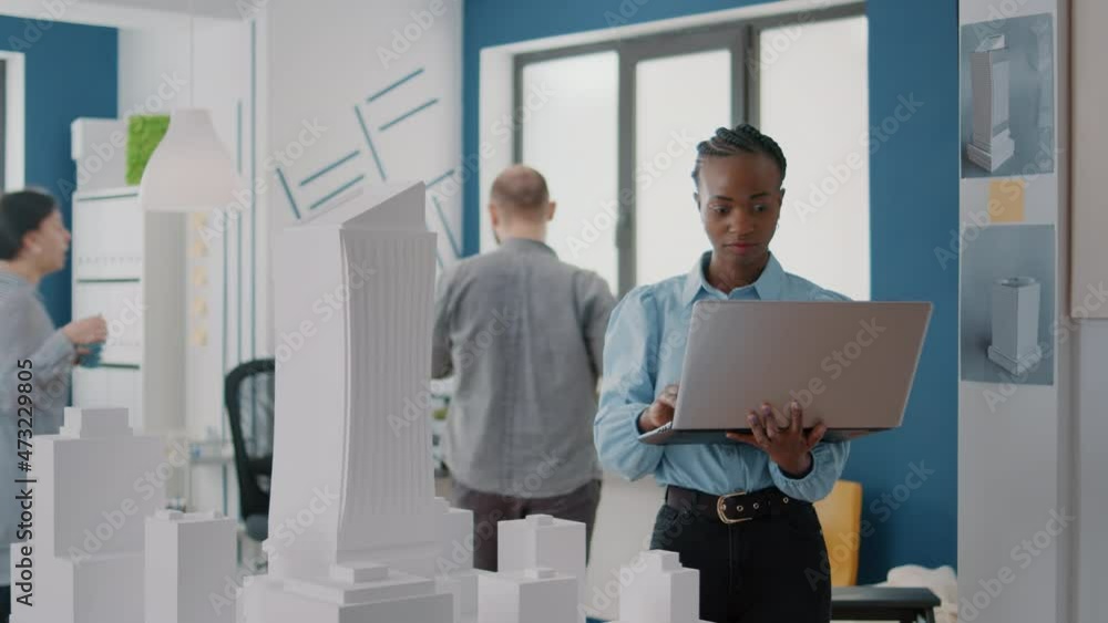 Poster woman engineer working on laptop to plan contruction layout with building model and maquette, design
