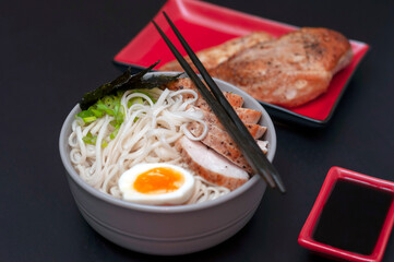 Ramen is a national, popular dish of traditional Japanese cuisine with chopsticks on a plate. Asian soup with wheat noodles, chicken breast, egg and broth.