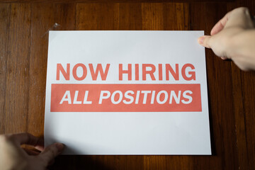 Now hiring sign on the wall